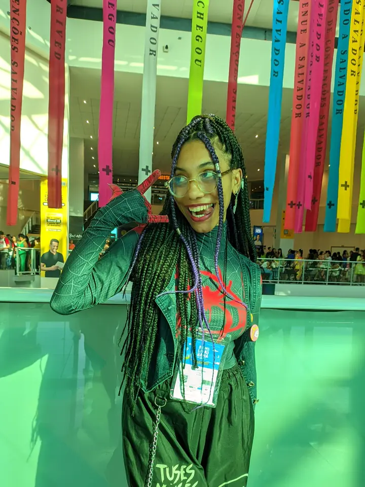 Júlia diante de fitas coloridas no espaço da Bienal da Bahia